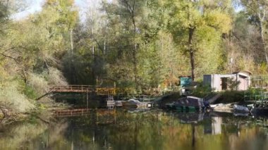 Ağaçların arka planına karşı sessiz bir zemin ve kıyıya yakın metal bir köprü..