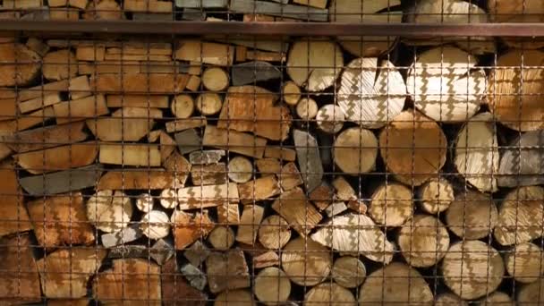 Logs and boards made of natural wood behind a metal grate close-up. — Stock Video