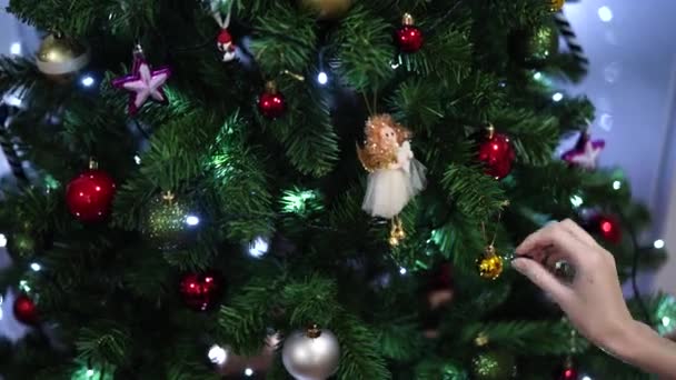 Preparando-se para celebrar o ano novo. Mãos femininas pendurar a bola na árvore de Natal. — Vídeo de Stock