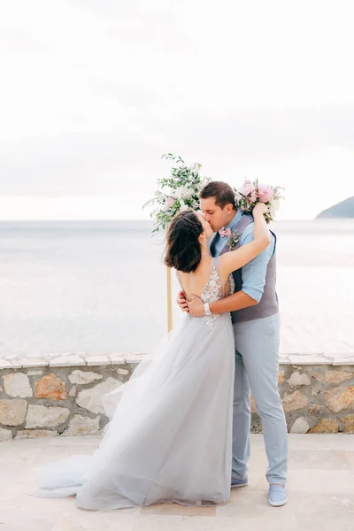 A menyasszony és a vőlegény ölelkeznek és csókolóznak a mólón. — Stock Fotó