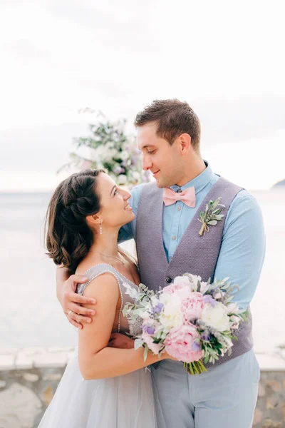 Braut und Bräutigam umarmen sich und schauen sich auf der Seebrücke an — Stockfoto