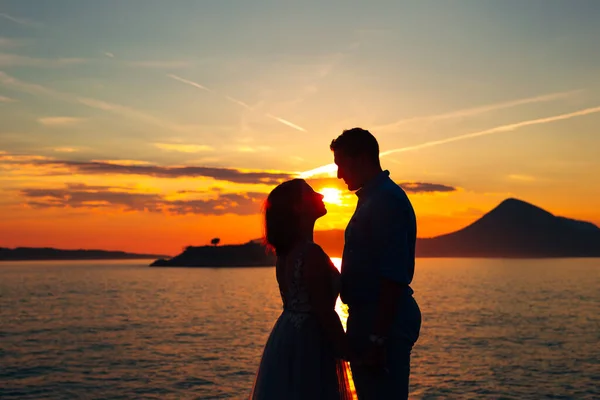 A noiva eo noivo de pé na praia da ilha Mamula e de mãos dadas ao pôr do sol — Fotografia de Stock