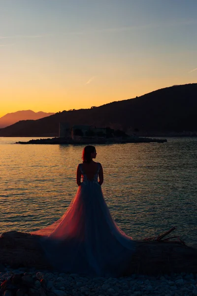 La mariée debout sur la plage de l'île Mamula sur le fond de la forteresse d'Arza au coucher du soleil — Photo