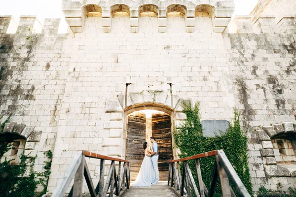 A menyasszony és a vőlegény ölelkeznek az ősi kapunál, közel az Arza erődhöz a Mamula szigeten. — Stock Fotó