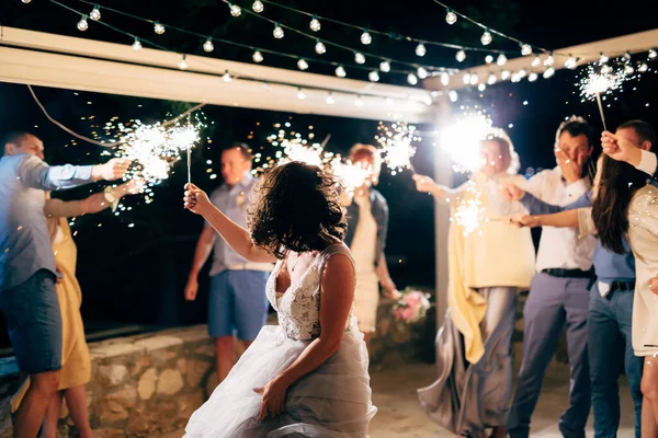 Menyasszony táncol a vendégek között csillagszórókkal az esküvői partin — Stock Fotó