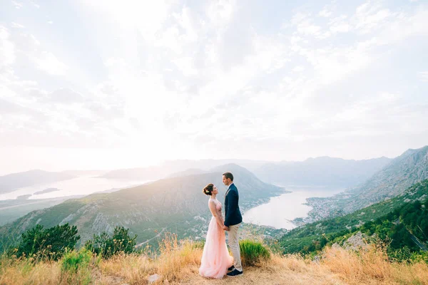 Bruid en bruidegom staan op de berg tegen de achtergrond van de baai van Kotor — Stockfoto