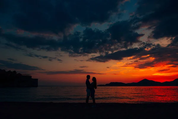 Чоловік і жінка обіймаються на пляжі під час заходу сонця — стокове фото