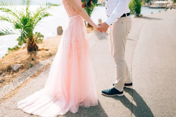 Nevěsta a ženich se na sebe dívají a drží se za ruce v perastu — Stock fotografie