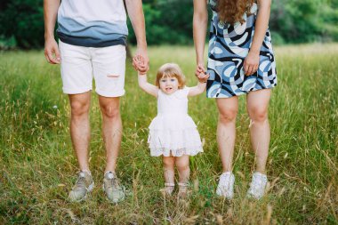 Anne ve baba kızı kollarından tutuyor.