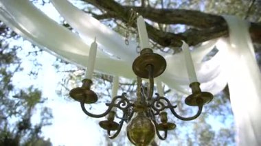 Candelabrum ve bahçedeki zeytin dalları üzerine havadar kumaş tuvalleri, düğün süslemeleri.