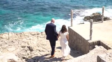 Gelin ve damat kayalık sahile iner ve el ele tutuşurlar.