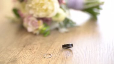 Gelin buketinin yanındaki masada alyanslar, damat yüzüğü dönüyor.