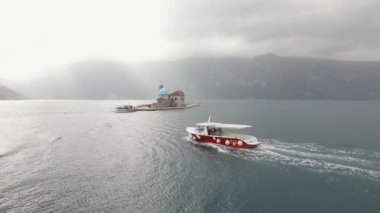 Perast yakınlarındaki Our Lady of the Rocks adasına giden turist teknesinin görüntüsü.