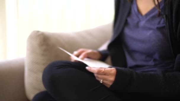 Mujer sentada en el sofá y leyendo una carta — Vídeos de Stock