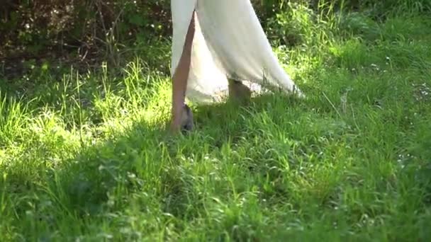 Panna młoda chodzi po trawie, jej spódnica pokazuje nogi — Wideo stockowe