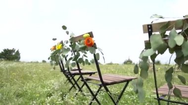 Düğün yeri, çiçekler ve okaliptüs yapraklarıyla süslenmiş sandalyeler.