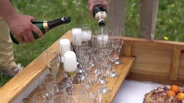 Свадебный банкет на открытом воздухе, двое мужчин наливают шампанское в бокалы — стоковое видео