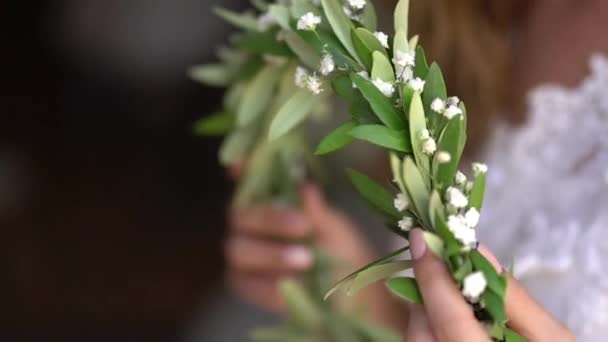 A noiva segura em suas mãos uma grinalda graciosa de murta florescente — Vídeo de Stock