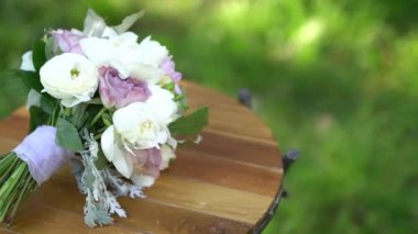 Gelin buketi, açık havada, ahşap bir ayakta duruyor.