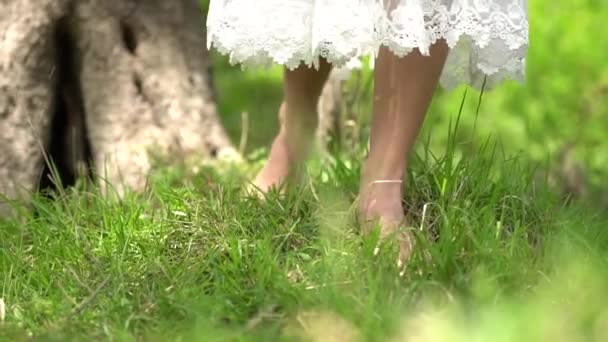 Barfota brud går på gräset, kjol fladdrar i vinden — Stockvideo