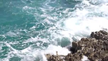 Kayalık sahil, dalgalar kayalara çarpıyor.