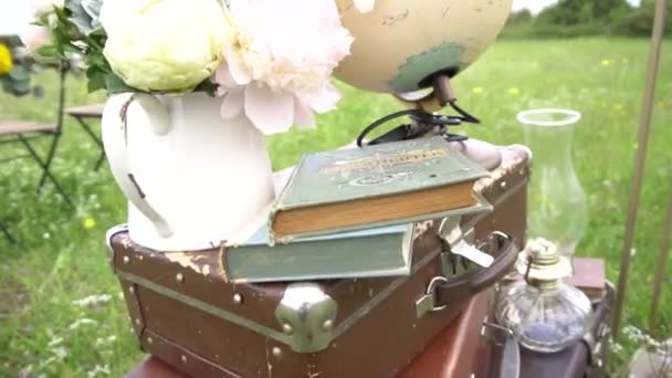 Bröllop dekorationer från gamla resväskor, böcker, bukett och en fotogenlampa — Stockvideo