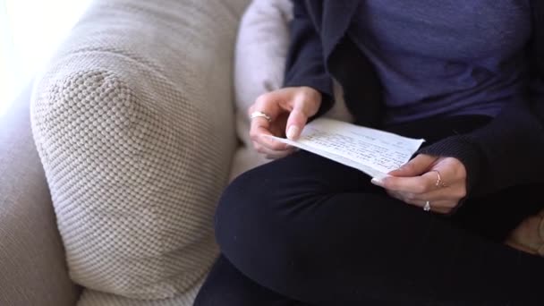 Frau sitzt auf der Couch und liest einen Brief — Stockvideo