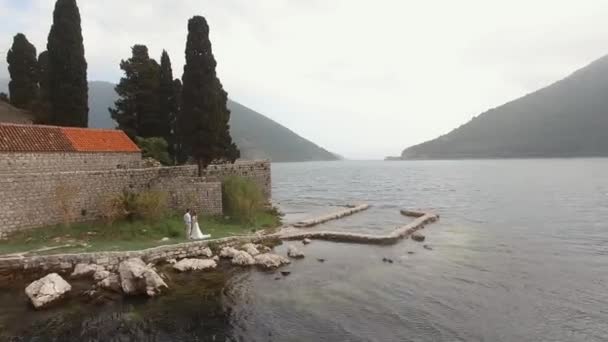 Vue sur l'île de Saint George près de Perast, jeunes mariés debout dessus — Video