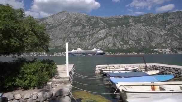 Toeristische lijnvaart in het midden van de baai van Kotor, vissersboten zijn afgemeerd aan de pier — Stockvideo