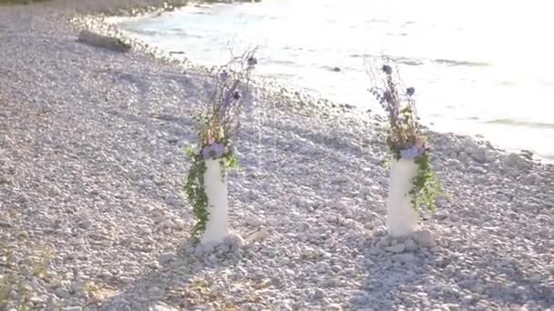 Lugar de la boda con arco y decoraciones en una playa de guijarros junto al mar — Vídeos de Stock