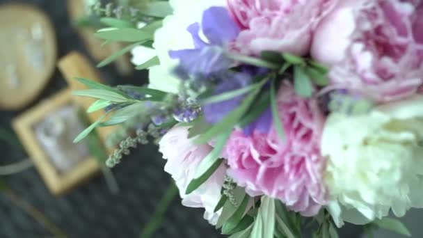 Букет наречених на столі, поруч з ним весільні кільця в ювелірній коробці та аксесуари — стокове відео