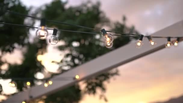 Dosel con guirnaldas de bombillas decorativas balanceándose en el viento — Vídeos de Stock