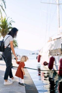 Anne ve kızı suuny bir günde marinada bir tekneye bakıyorlar.