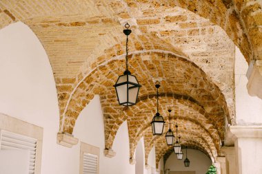 Koridorun tavanındaki kemerli açıklıkta asılı ışıklar..