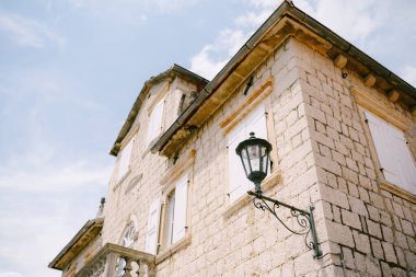 Binanın duvarına asılı sokak lambası, balkon ve çatı pencerelerinin yanında..