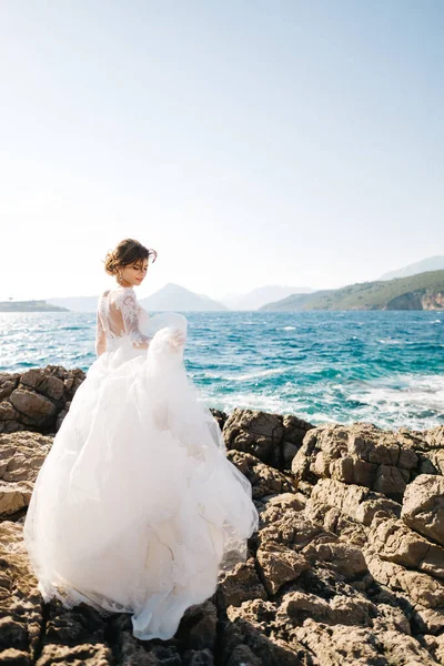 Mamula adasının kayalık sahilinde yumuşak gelinlik içinde güzel bir gelin. — Stok fotoğraf