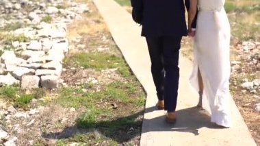 Gelin ve damat el ele kumsala doğru yürüyorlar.