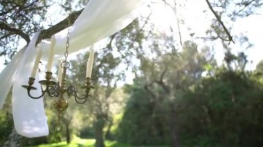 Candelabrum ve bahçedeki zeytin dalları üzerine havadar kumaş tuvalleri, düğün süslemeleri.