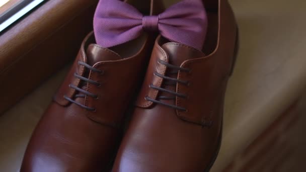 Sapatos de couro marrom e os noivos arco gravata stand no peitoril da janela enquanto se prepara — Vídeo de Stock