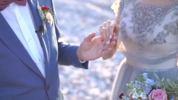 Ο γαμπρός κρατάει το χέρι της νύφης, η νύφη έχει ένα δαχτυλίδι στο δάχτυλό της — Αρχείο Βίντεο