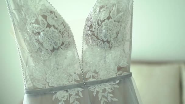 Vestido de novia de encaje con un escote profundo cuelga en la habitación del hotel durante la preparación para la ceremonia de boda — Vídeos de Stock