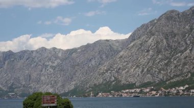 Kotor Körfezi 'nin sahil ve manzaralı dağları, eski kasaba, yelkenli ve yol tabelası, zaman kavramı.