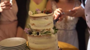 Gelin ve damat düğün pastasını kesti, pasta çiçeklerle, böğürtlenlerle ve zeytinlerle süslendi.