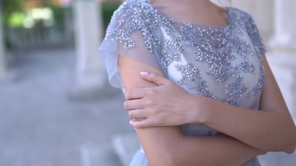 De bruid in een elegante jurk geborduurd met kralen gevouwen haar armen over haar borst — Stockvideo