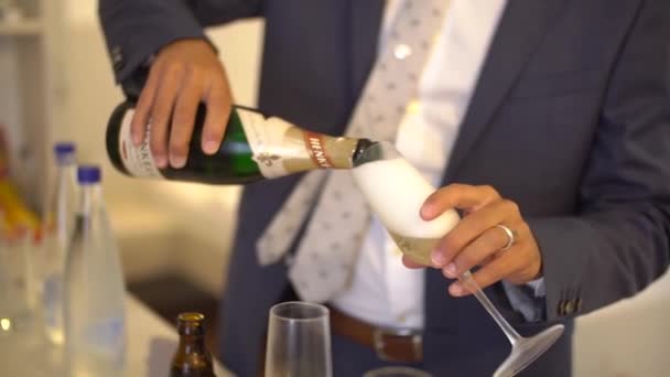 Un bărbat în costum cu cravată toarnă șampanie într-un pahar, aproape — Videoclip de stoc