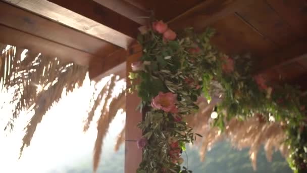 Деревянная беседка, украшенная цветами, пальмовые ветви на крыше — стоковое видео