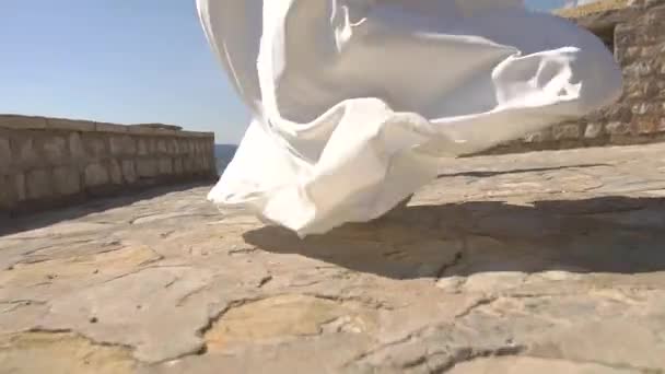 De bruid loopt langs het stenen platform naar de bruidegom, de rok van haar jurk fladdert in de wind — Stockvideo