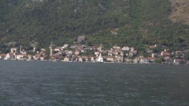 Beyaz yelkenli Kotor Körfezi 'ndeki küçük bir kasabanın yanında.