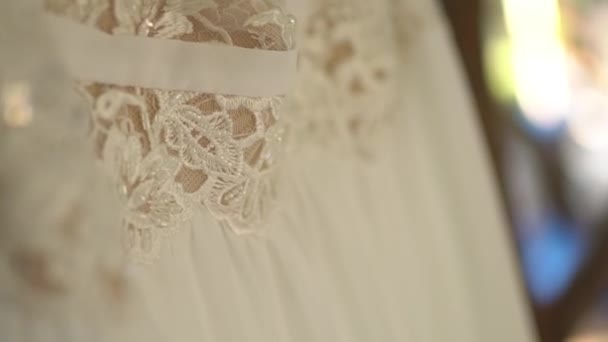 Lace wedding dress with beaded bodice hanging on tree branches among the foliage — Stock Video