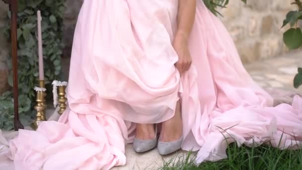 Bride in a pink wedding dress lifts her skirt to reveal gray shoes — Stockvideo